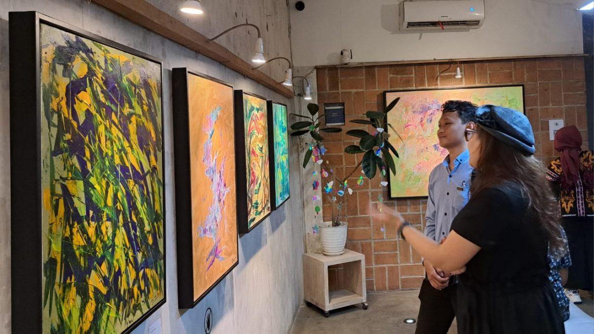 Fiya Ardia (kanan, bertopi) berbincang dengan penikmat lukisannya yang ia pamerkan di Semarang.