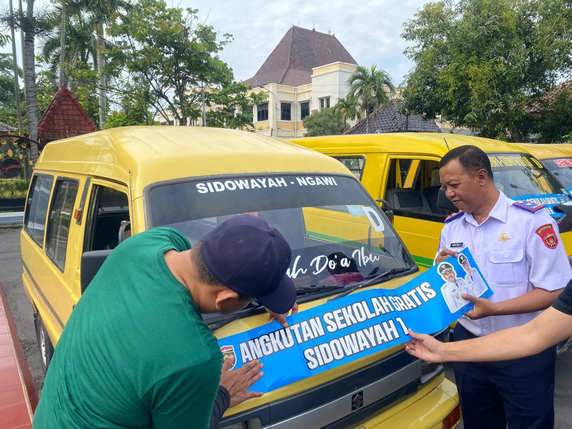 Bupati Ngawi, Ony Anwar Harsono (kiri), menempelkan stiker tanda Angkutan Sekolah Gratis.